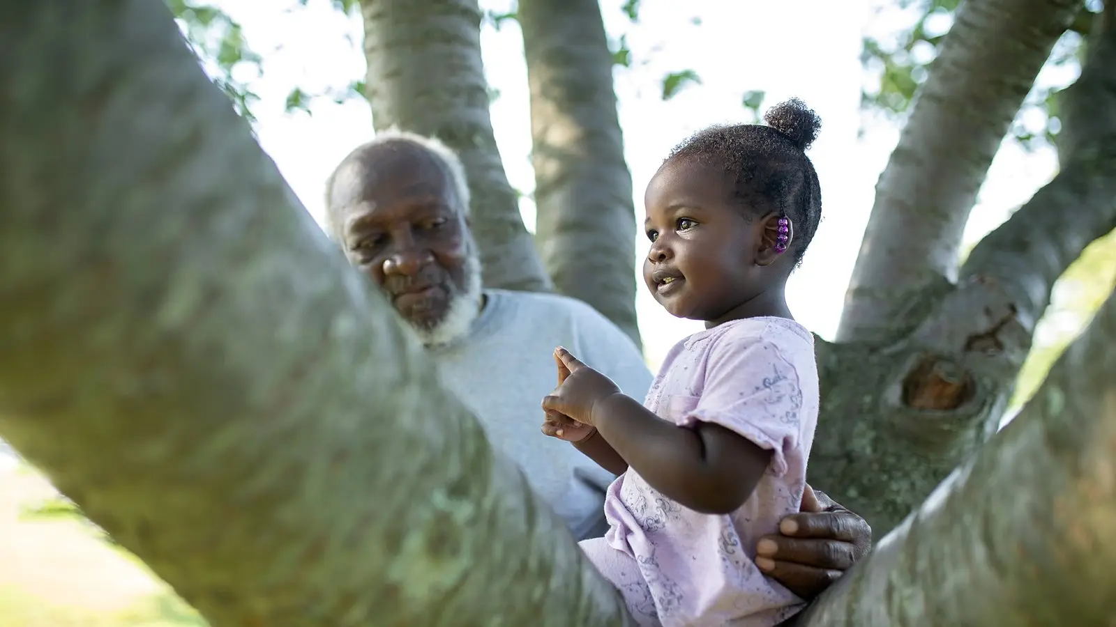 A grandfather sharing a happy moment with his granddaughter outdoors