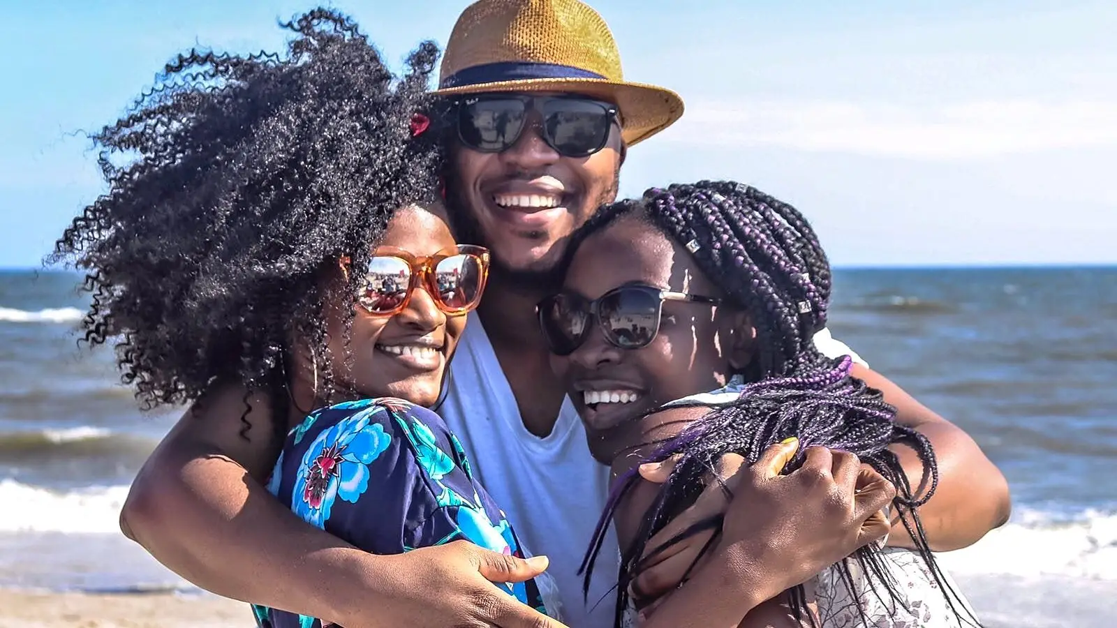 A family hugging and smiling together on a beach holiday