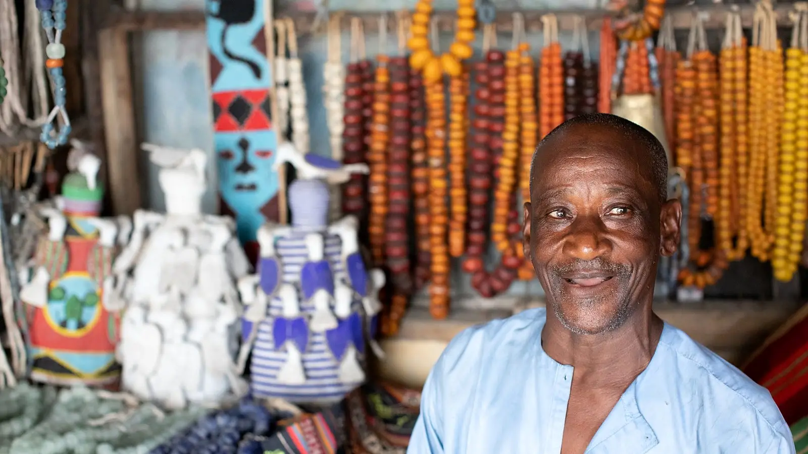 An older trader smiling in his shop at a Nigerian craft market