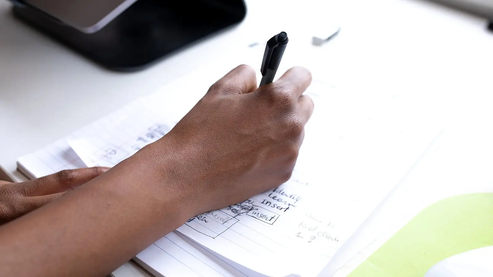 A hand signing off a document at an office desk